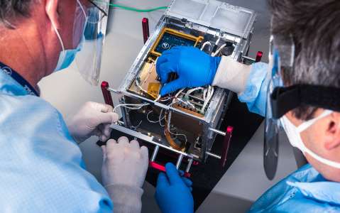 Image of scientists working on satellite payload
